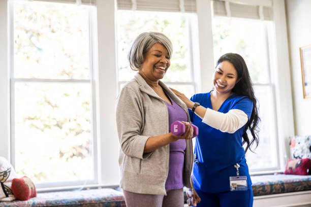 At home nurse helping senior woman with physical therapy at home